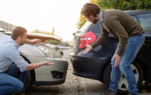 Two persons checking their cars after a rear-end collision
