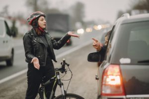 a man sitting on car and a cyclist girl are talking